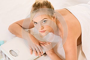 Blonde woman in spa holding on weight scales