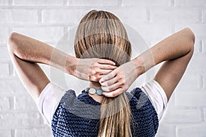 A blonde woman standing with her back touches her long hair