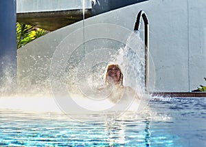 A blonde woman is standing under a strong jet of water