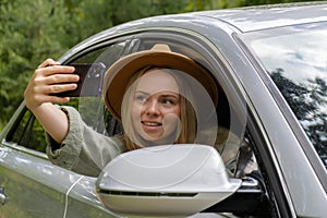 Blonde woman stoped car on road to take a selfie photo. Young tourist explore local travel making candid real moments