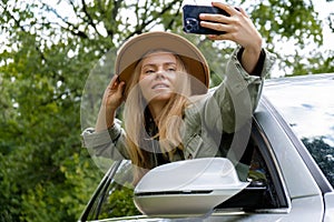 Blonde woman stoped car on road to take a selfie photo. Young tourist explore local travel making candid real moments