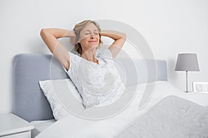 Blonde woman stretching and smiling in bed