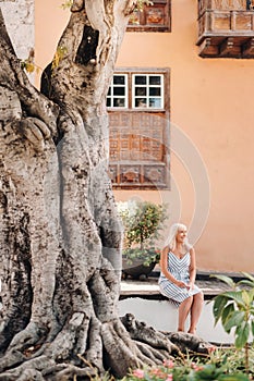 A blonde woman in a sundress sits on the street of the Old town of Garachico on the island of Tenerife.Spain, Canary Islands