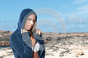 Blonde woman with sweatshirt and hood at the seashore