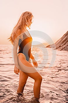 Blonde woman in swimwear bikini on quiet sea with sunset colors. Girl on vacation