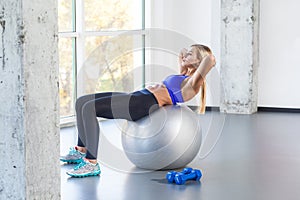 Blonde woman swing press on fit ball.