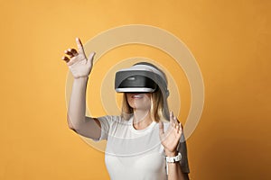 Blonde woman in t-shirt is VR glasses technology advanced user operates in augmented virtual reality pressing button