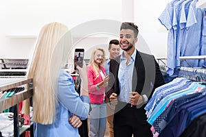 Blonde Woman Taking Photo Of Young People Shopping, Happy Smiling Friends Customers In Fashion Shop
