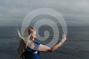 Blonde woman taking photos with her phone