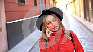 Blonde woman talking on her smartphone while walking down the street.