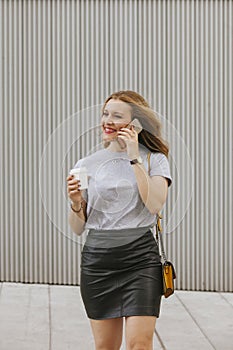 blonde woman talking to her phone while drinking coffee