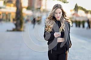 Blonde woman texting with her smartphone in urban background