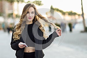Blonde woman texting with her smartphone in urban background