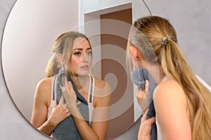 Blonde woman with towel looking in mirror
