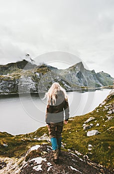 Blonde woman traveler walking alone at lake mountains