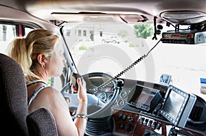 Blonde woman truck driver talking on her radio.