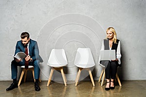 Blonde woman using laptop while waiting job interview near man