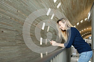 Blonde woman using smartphone in monophonic background.