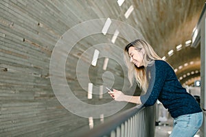 Blonde woman using smartphone in monophonic background.