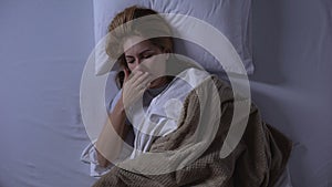 Blonde woman waking-up in morning feeling nausea, morning sickness, top-view