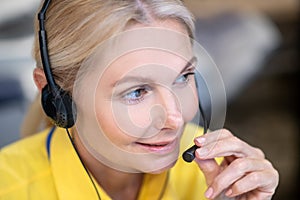 Blonde woman wearing headphones, speaking into microphone