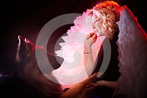 Blonde woman with white angel wings and a large German shepherd dog. Photo shoot in studio