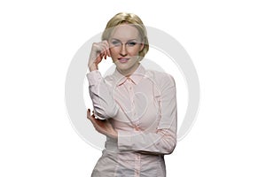 Blonde woman in white blouse standing up resting her head on her hand on white background.