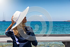 Blonde woman with white hat enjoys her summer holiday at the blue sea