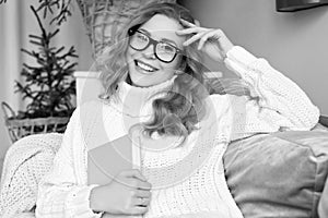 Blonde woman in white woolen sweater and glasses reading book