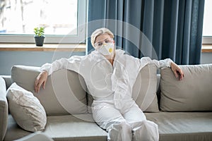 Blonde woman in white workwear and respirator looking exhausted