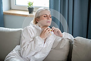 Blonde woman in white workwear sitting on the sofa