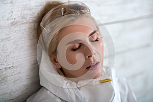 Blonde woman in white workwear sufferning from headache