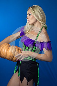 Blonde woman in a witch costume holding pumpkin in her hands