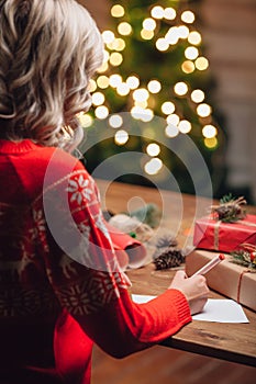 Blonde woman writing on christmas postcard