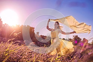 Blonde woman in a yellow dress in lavender field at sunset