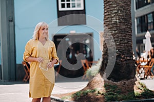 A blonde woman in a yellow summer dress stands on the street of the Old town of La Laguna on the island of Tenerife.Spain, Canary