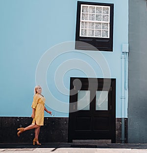 A blonde woman in a yellow summer dress stands on the street of the Old town of La Laguna on the island of Tenerife.Spain, Canary
