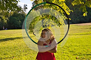 Blonde woman and young gymnast acrobat athlete performing aerial exercise on air ring outdoors in park. Flexible woman in red