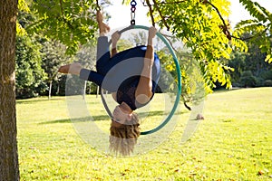 Blonde woman and young gymnast acrobat athlete performing aerial exercise on air ring outdoors in park. Lithe woman in blue photo