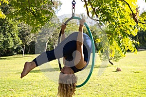 Blonde woman and young gymnast acrobat athlete performing aerial exercise on air ring outdoors in park. Lithe woman in blue photo