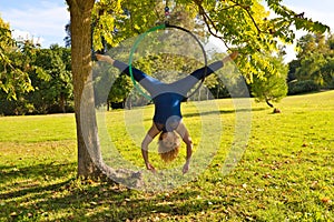 Blonde woman and young gymnast acrobat athlete performing aerial exercise on air ring outdoors in park. Lithe woman in blue photo