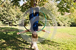 Blonde woman and young gymnast acrobat athlete performing aerial exercise on air ring outdoors in park. Lithe woman in blue photo