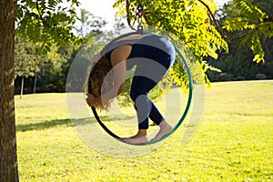 Blonde woman and young gymnast acrobat athlete performing aerial exercise on air ring outdoors in park. Lithe woman in blue photo