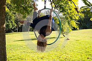 Blonde woman and young gymnast acrobat athlete performing aerial exercise on air ring outdoors in park. Lithe woman in blue photo