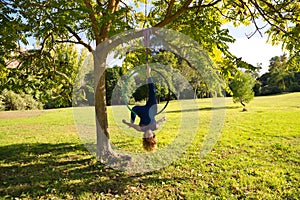 Blonde woman and young gymnast acrobat athlete performing aerial exercise on air ring outdoors in park. Lithe woman in blue