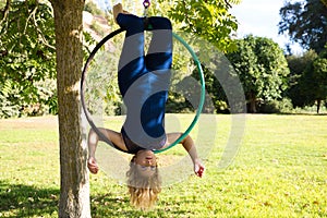 Blonde woman and young gymnast acrobat athlete performing aerial exercise on air ring outdoors in park. Lithe woman in blue