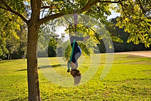 Blonde woman and young gymnast acrobat athlete performing aerial exercise on air ring outdoors in park. Lithe woman in blue