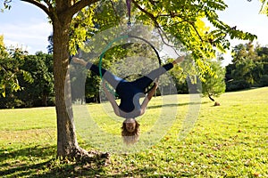 Blonde woman and young gymnast acrobat athlete performing aerial exercise on air ring outdoors in park. Lithe woman in blue photo