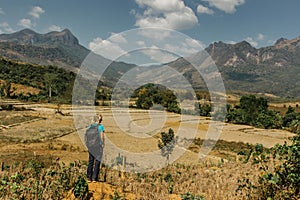 Blonde young girl hiking in Laotian mountains. Beautiful view of Laos landscape, spring valley, rice fields and Asian