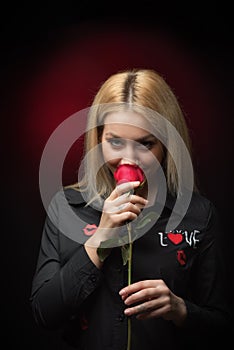 Blonde young smiling woman smelling red rose